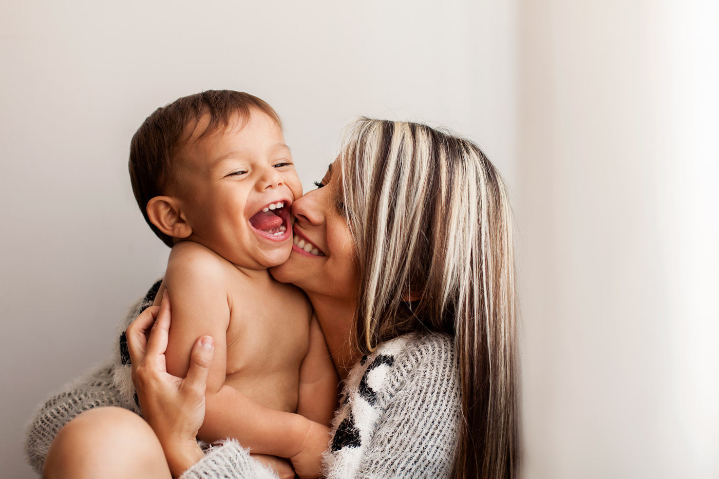 Parent hugging a toddler and smiling.