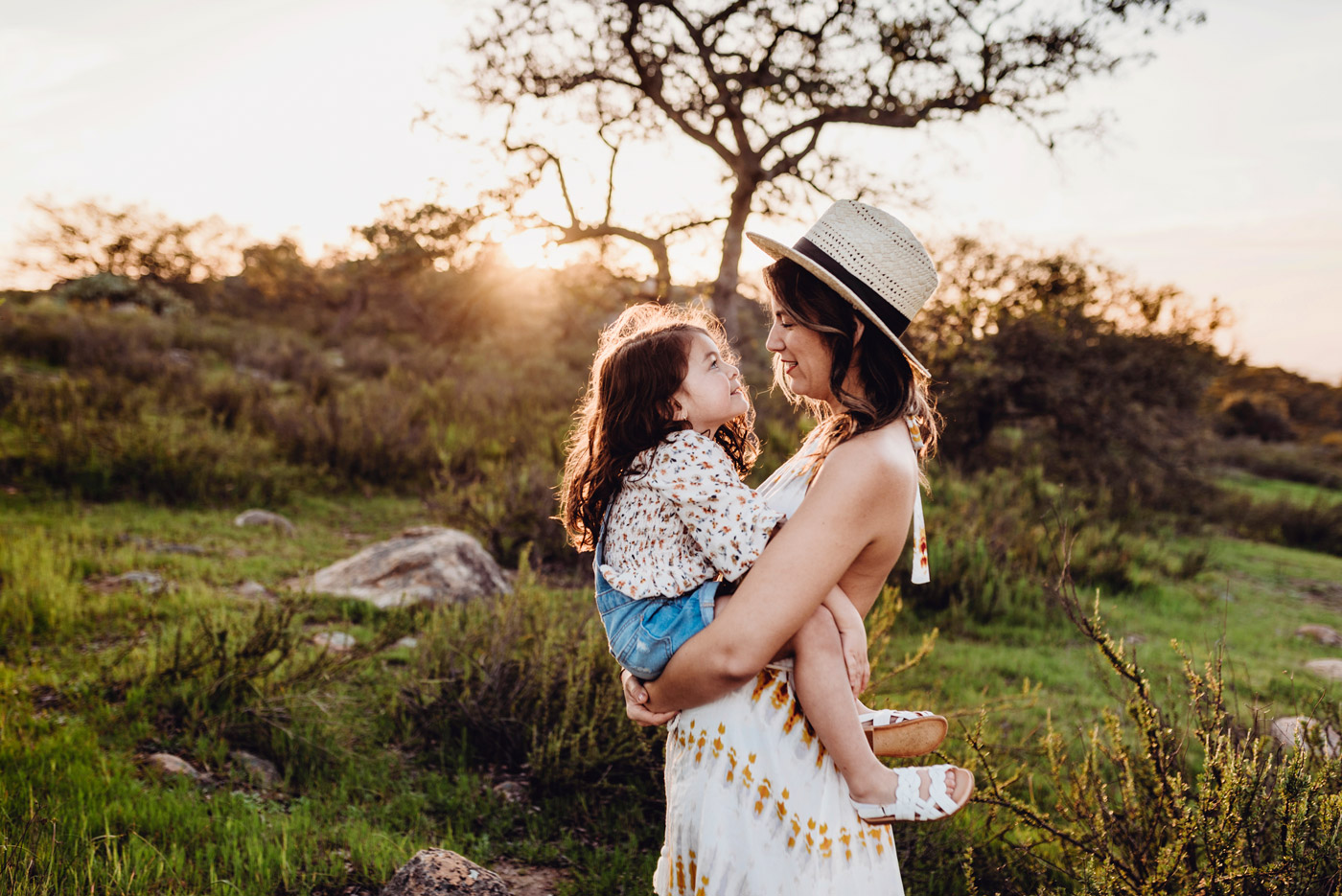 Mother hold child outside in a field at sunset